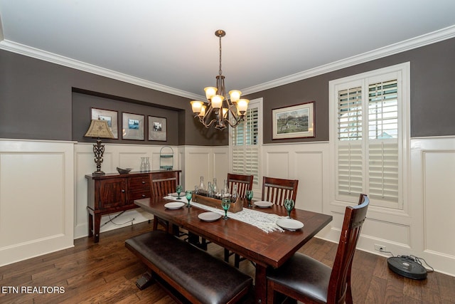 dining area with a wainscoted wall, a notable chandelier, ornamental molding, a decorative wall, and dark wood-style flooring