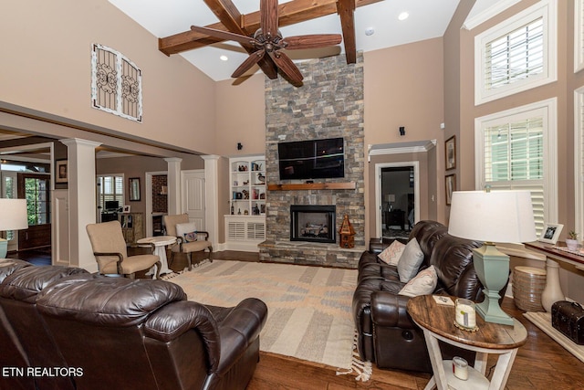 living area with beam ceiling, a healthy amount of sunlight, wood finished floors, and a fireplace