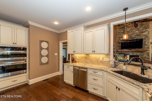 kitchen with dark wood-style floors, a sink, appliances with stainless steel finishes, crown molding, and backsplash