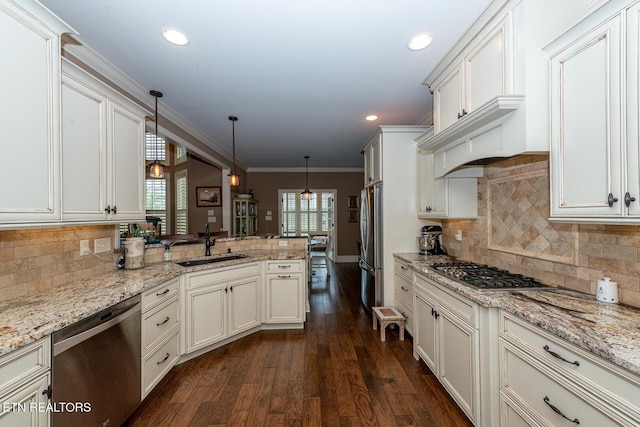 kitchen featuring dark wood finished floors, a peninsula, a sink, ornamental molding, and stainless steel appliances