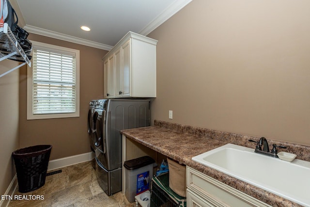 washroom with baseboards, cabinet space, a sink, crown molding, and washing machine and dryer