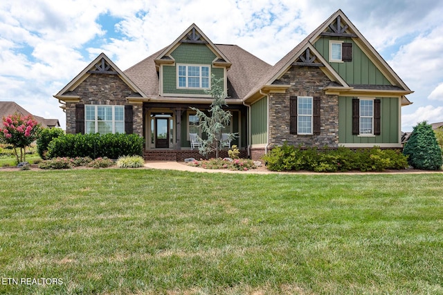 craftsman-style house featuring a porch, stone siding, board and batten siding, and a front lawn