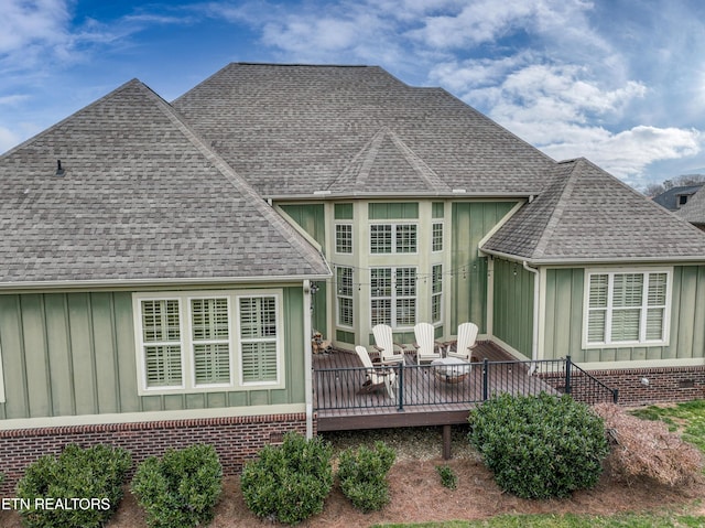 rear view of property featuring brick siding, board and batten siding, and a shingled roof