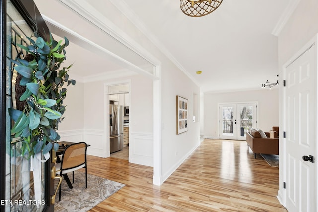 entryway featuring french doors, light wood-type flooring, and ornamental molding