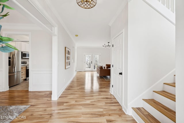 entrance foyer with stairway, french doors, light wood-type flooring, and ornamental molding