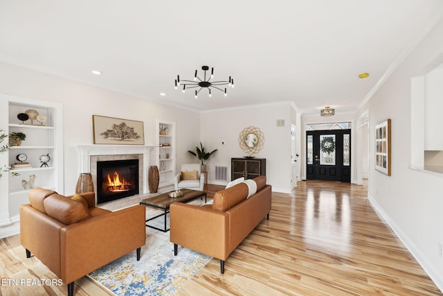 living room with built in features, crown molding, light wood-type flooring, and baseboards