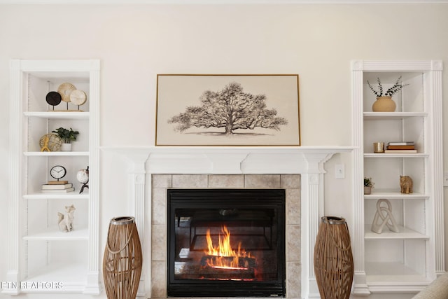 interior details with a tiled fireplace and built in shelves