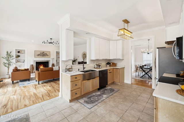 kitchen featuring ornamental molding, a tiled fireplace, a sink, stainless steel appliances, and light countertops