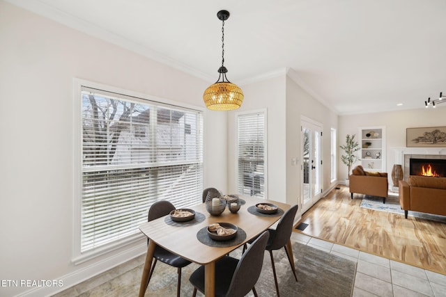 dining space featuring built in shelves, ornamental molding, a fireplace, light tile patterned floors, and baseboards