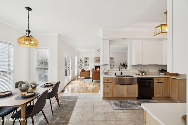 kitchen featuring light tile patterned floors, a lit fireplace, a sink, light countertops, and black dishwasher