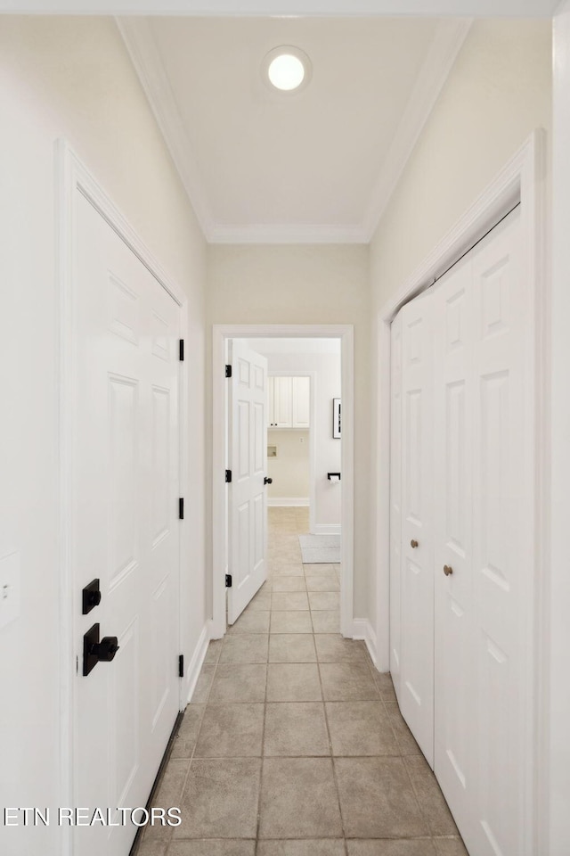 hallway featuring light tile patterned floors, baseboards, and ornamental molding