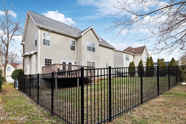 back of property featuring a wooden deck, a lawn, and fence private yard