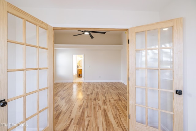 spare room featuring light wood finished floors, baseboards, and a ceiling fan