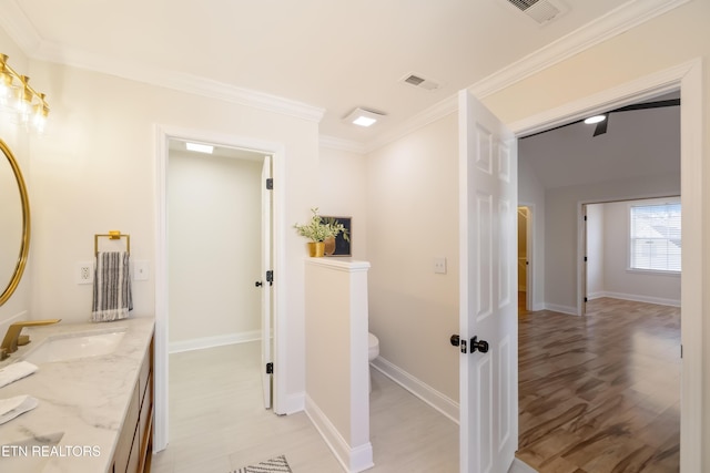 hallway featuring visible vents, crown molding, baseboards, and a sink