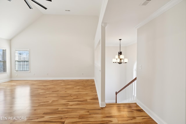 empty room featuring baseboards, ceiling fan with notable chandelier, visible vents, and light wood-type flooring