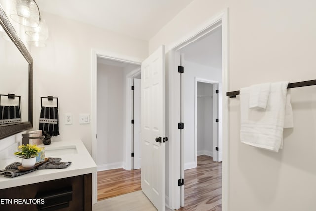 bathroom with vanity, wood finished floors, and baseboards