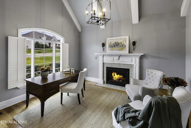 office space with baseboards, a tiled fireplace, lofted ceiling with beams, an inviting chandelier, and wood finished floors