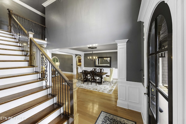 entryway with ornate columns, wainscoting, a towering ceiling, and wood finished floors