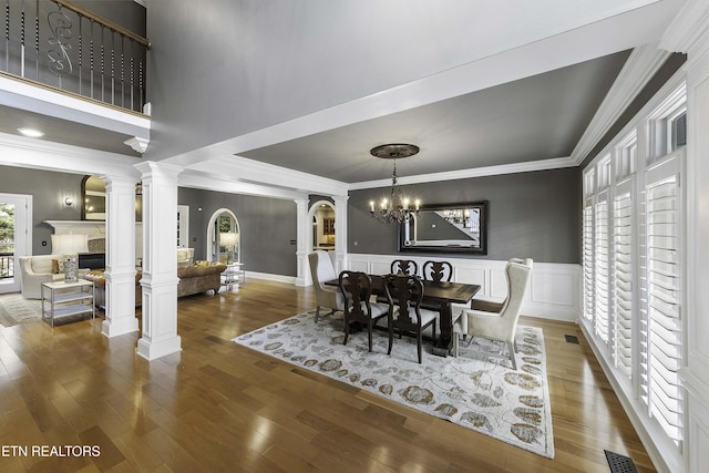 dining room with visible vents, ornamental molding, wainscoting, wood finished floors, and ornate columns