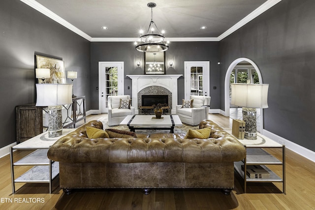 living area featuring a glass covered fireplace, wood finished floors, baseboards, and ornamental molding