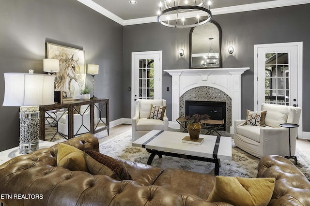 living room featuring wood finished floors, baseboards, a premium fireplace, ornamental molding, and a chandelier