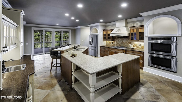 kitchen with a sink, a breakfast bar area, stainless steel appliances, and premium range hood