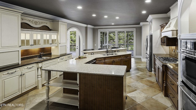 kitchen featuring a kitchen island with sink, recessed lighting, appliances with stainless steel finishes, arched walkways, and a sink