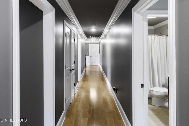 corridor with crown molding, wood finished floors, and baseboards