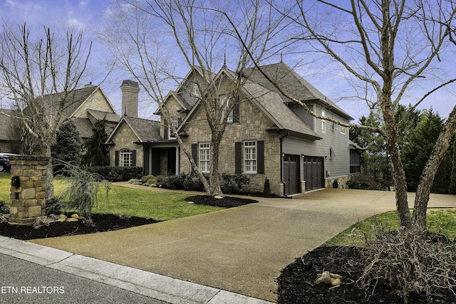 view of front of house featuring stone siding, concrete driveway, a garage, and a front yard