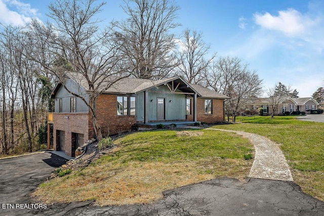 view of front of home featuring a garage, a front lawn, brick siding, and driveway