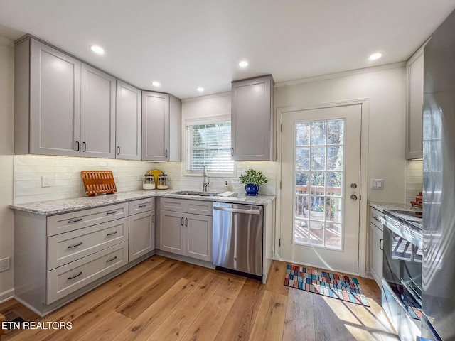 kitchen with a sink, tasteful backsplash, light wood-style floors, and appliances with stainless steel finishes