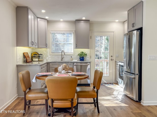 kitchen featuring a sink, gray cabinets, backsplash, and stainless steel appliances