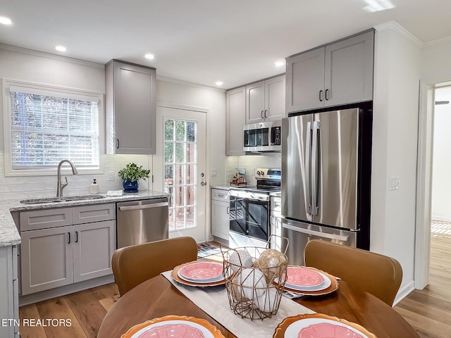 kitchen featuring light wood-style flooring, gray cabinetry, appliances with stainless steel finishes, and a sink