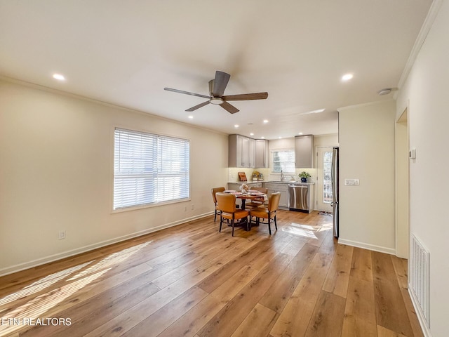 dining space featuring light wood finished floors, visible vents, crown molding, and a wealth of natural light