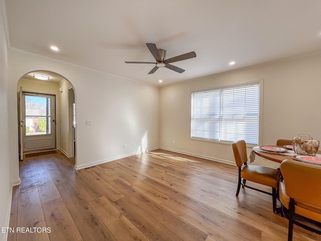 unfurnished dining area with arched walkways, light wood-type flooring, and ornamental molding