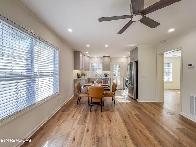 dining room with baseboards, light wood-type flooring, and ornamental molding