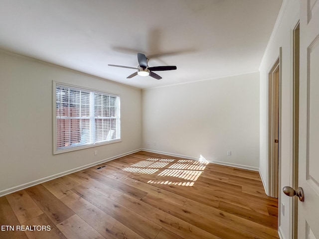 spare room featuring a ceiling fan, hardwood / wood-style flooring, crown molding, and baseboards