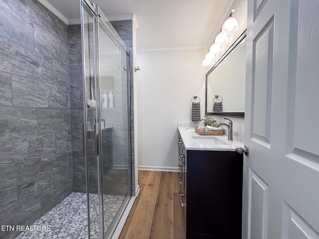 full bathroom with a shower stall, wood finished floors, crown molding, and a sink