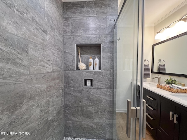 bathroom featuring double vanity, ornamental molding, a tile shower, and a sink