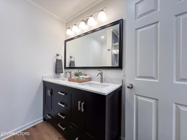 full bath with ornamental molding, wood finished floors, baseboards, and a sink