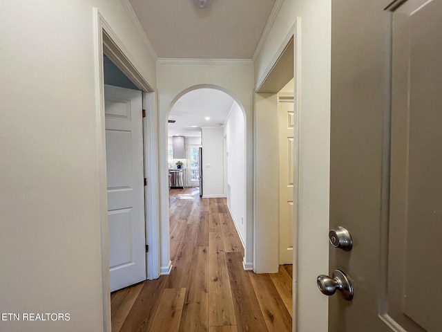 hall with baseboards, wood finished floors, arched walkways, and ornamental molding