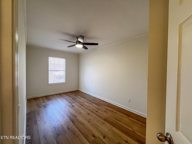 spare room with crown molding, baseboards, dark wood-type flooring, and ceiling fan