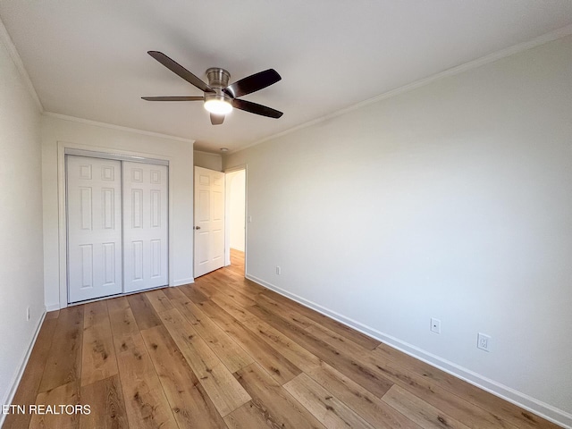 unfurnished bedroom featuring baseboards, light wood-type flooring, a closet, and ornamental molding