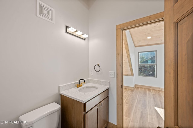 half bathroom featuring vanity, wood finished floors, visible vents, wooden ceiling, and toilet