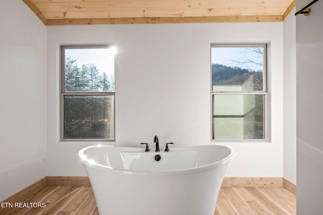 bathroom featuring a soaking tub, wooden ceiling, and wood finished floors