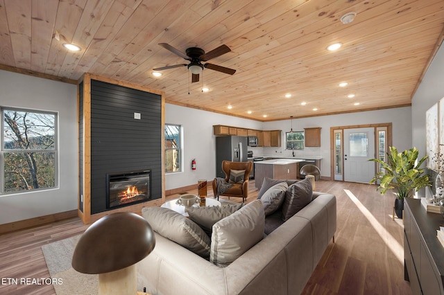 living area with baseboards, light wood finished floors, recessed lighting, wood ceiling, and crown molding