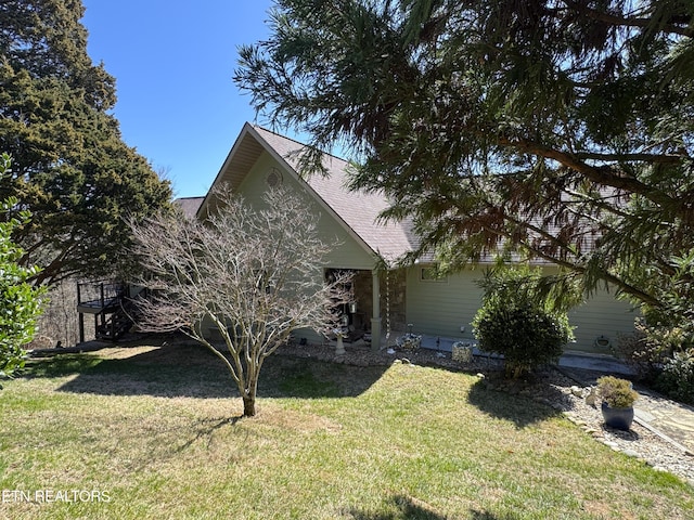 view of front facade featuring a front yard and a shingled roof