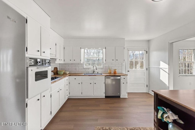 kitchen with a sink, appliances with stainless steel finishes, dark wood finished floors, and white cabinets