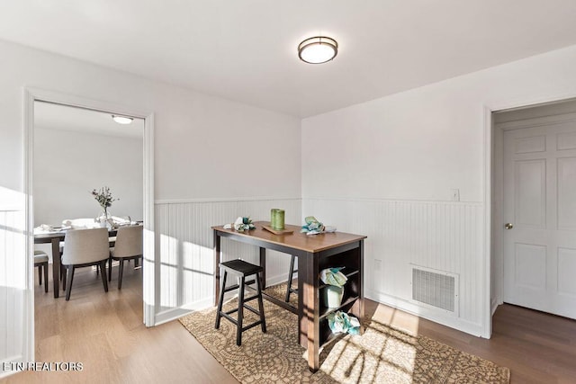 dining room featuring visible vents, wood finished floors, and wainscoting