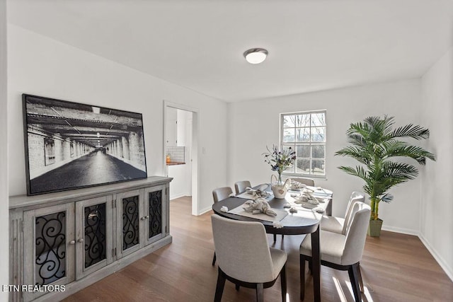 dining space with baseboards and wood finished floors